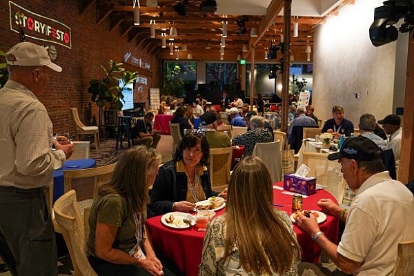 StoryFest Director Daria Sommers talking to veterans Joy Bronson and Ellen Haring while they eat dinner.