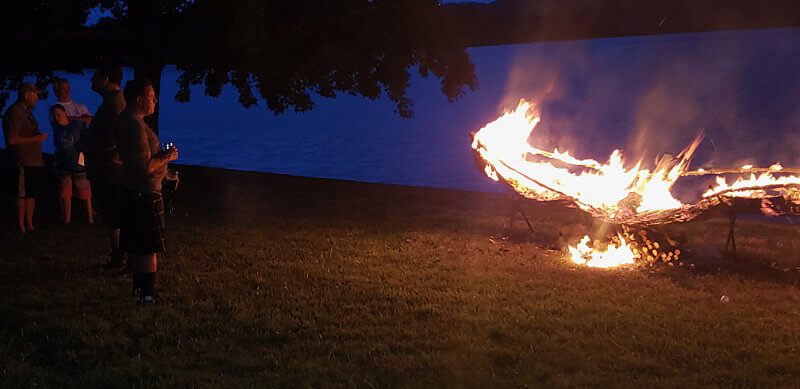 Mourners watch as a fire blazes for Andrew McCaffrey’s Viking Funeral