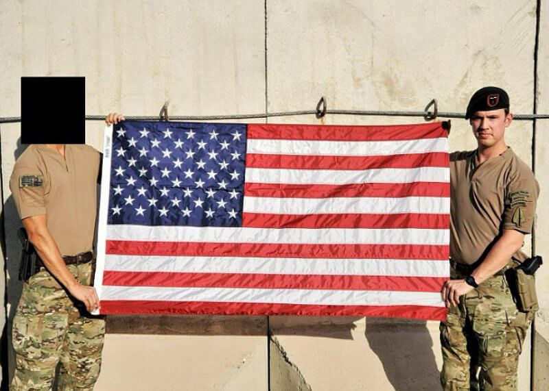 Long time history buff Nate Webster holding a US flag with the help of another soldier