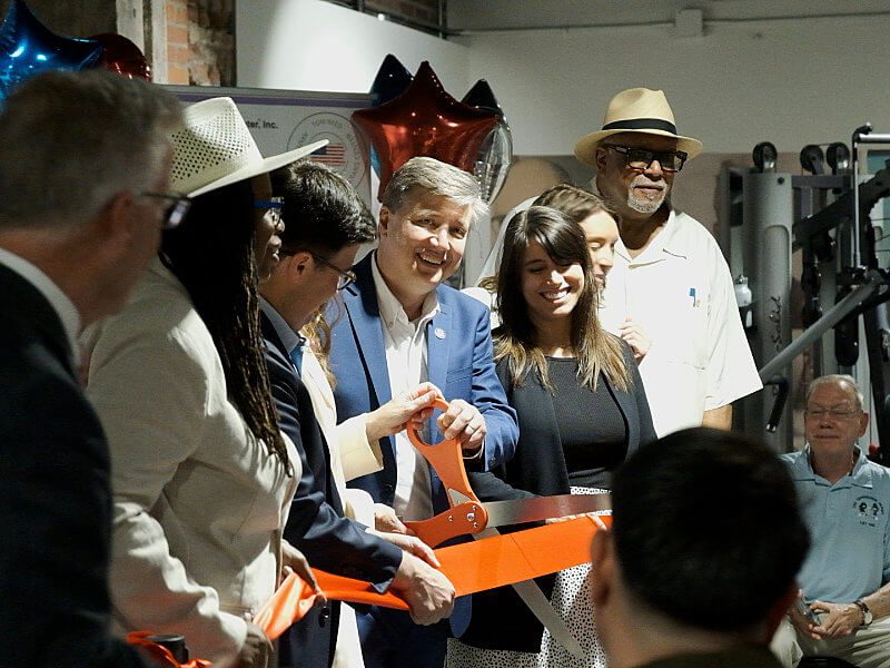 Todd DePastino on stage with others cutting the opening day ribbon